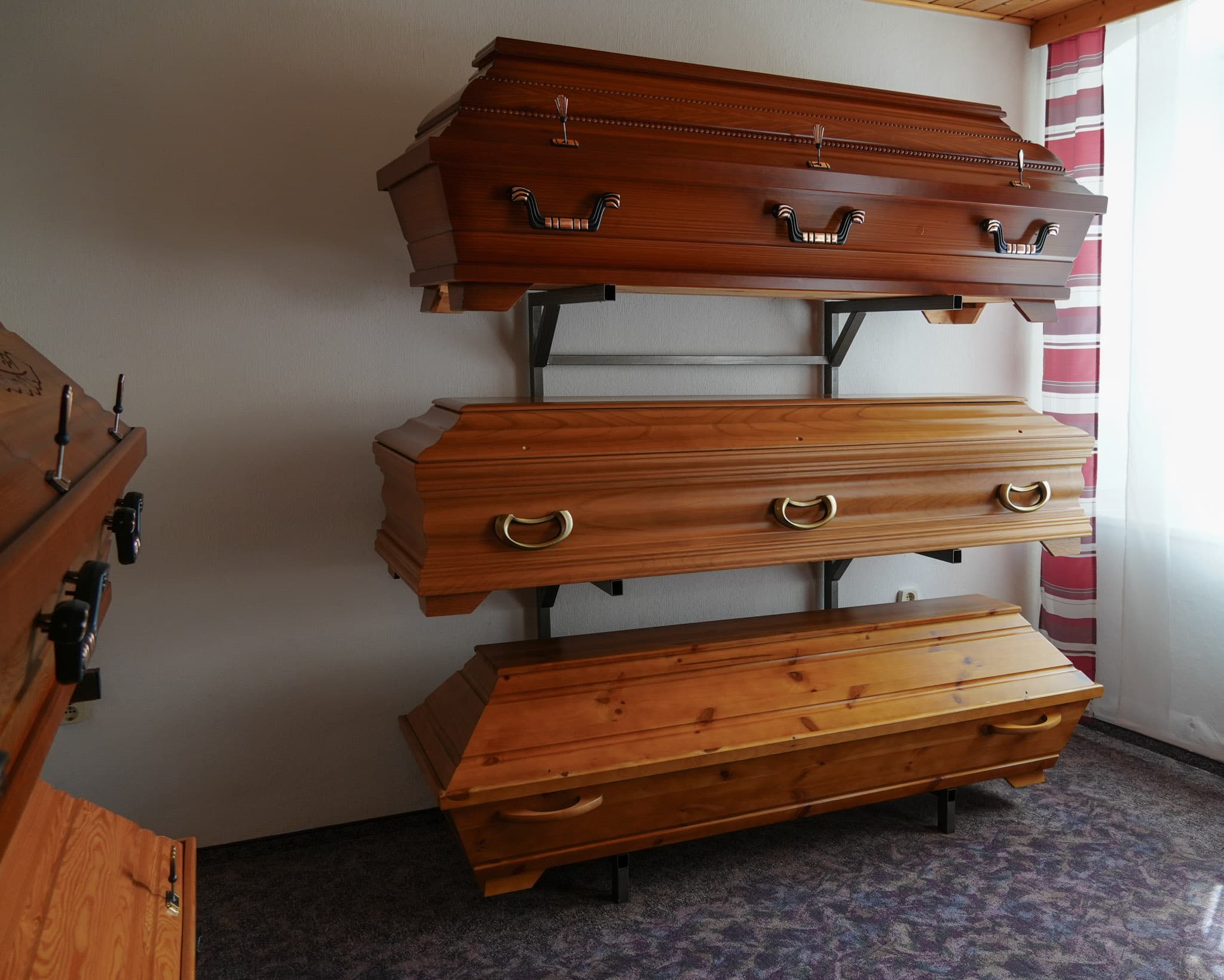 Drei Ausgestelle Särge an einer Wand