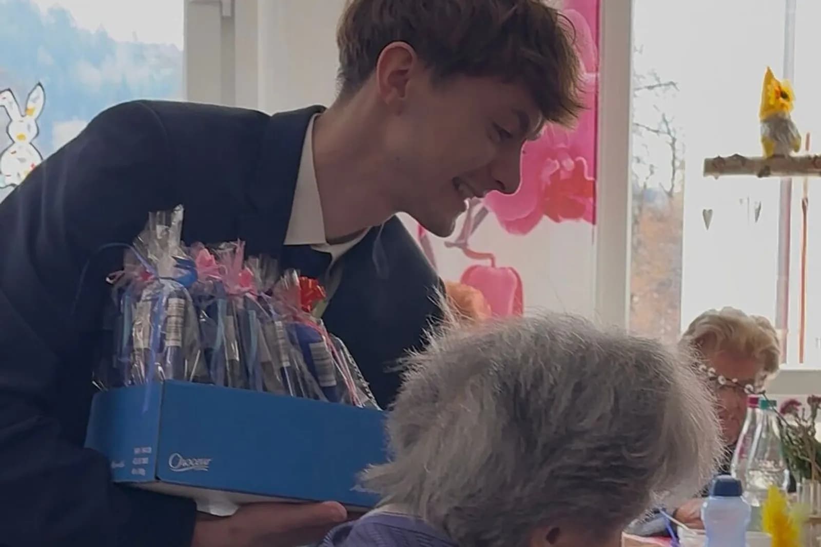 Mitarbeiter überreicht Geschenkbox an Seniorin